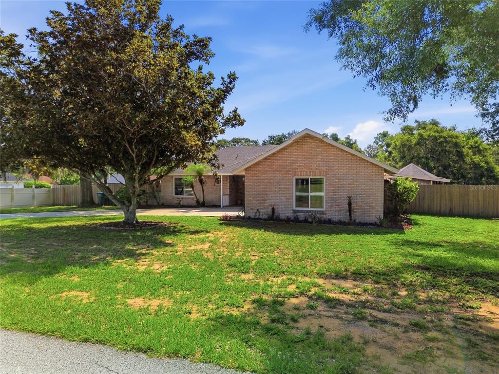 A single-story brick house with a large tree in the front yard — 17522 HILLSIDE DRIVE, MONTVERDE, FL