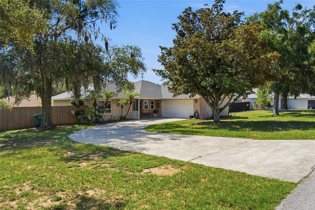 A covered brick porch features a white front door, a welcome sign, and a wooden bench — 17522 HILLSIDE DRIVE, MONTVERDE, FL