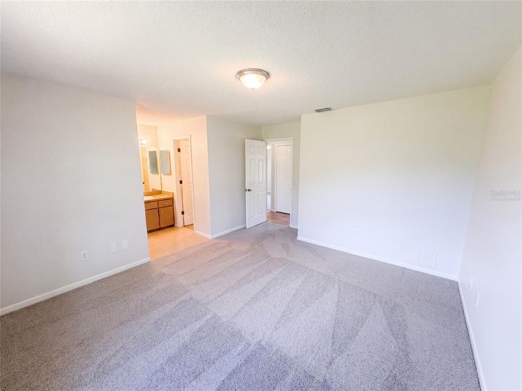 A carpeted bedroom features a ceiling light, a doorway to a bathroom, and a closet door — 1061 HUNT STREET NW, PALM BAY, FL