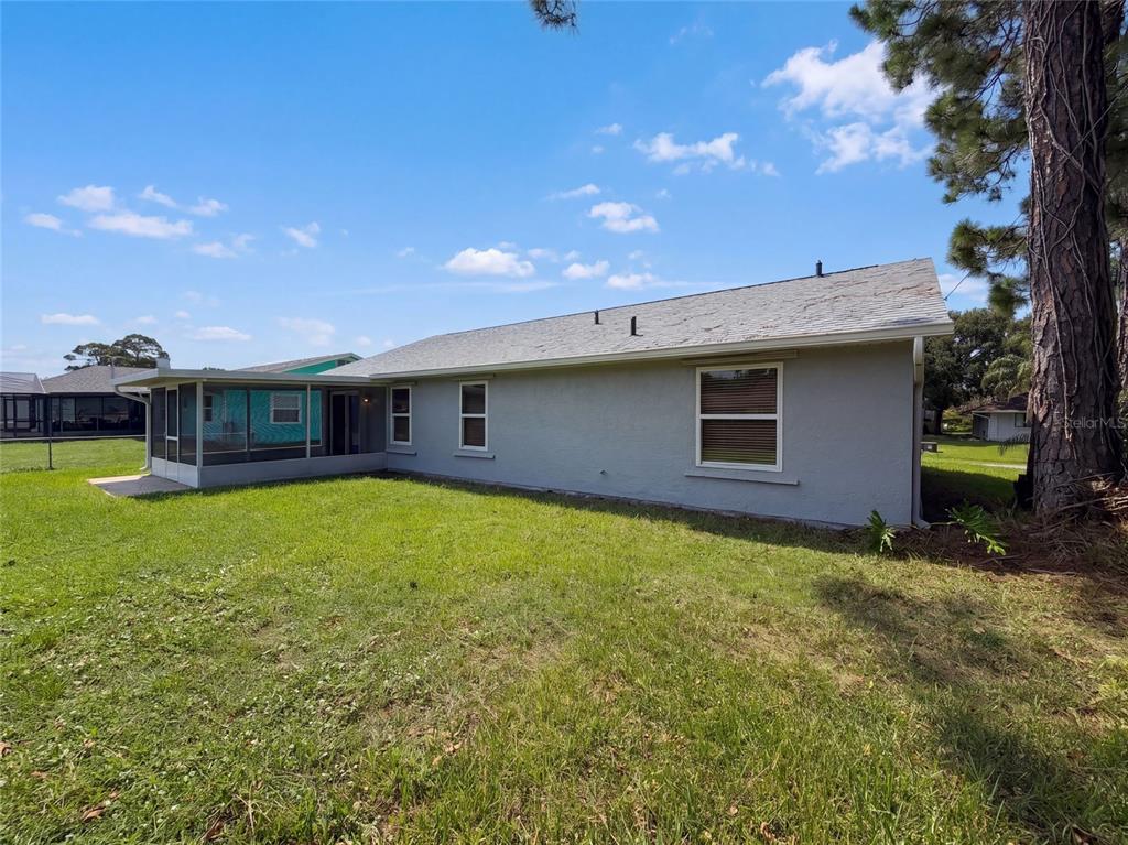 The exterior of a gray house features a screened-in porch and a grassy backyard — 1061 HUNT STREET NW, PALM BAY, FL