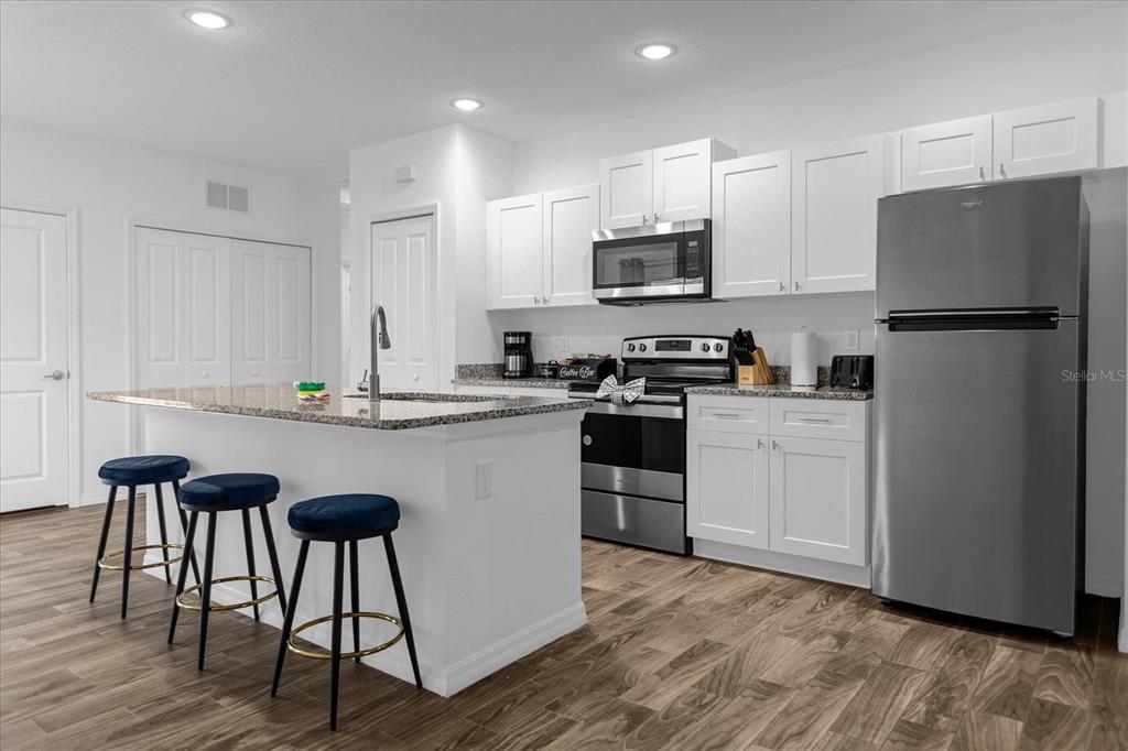 A modern kitchen features white cabinets, granite countertops, stainless steel appliances, and a breakfast bar — 97 N GOLDWYN AVENUE, ORLANDO, FL