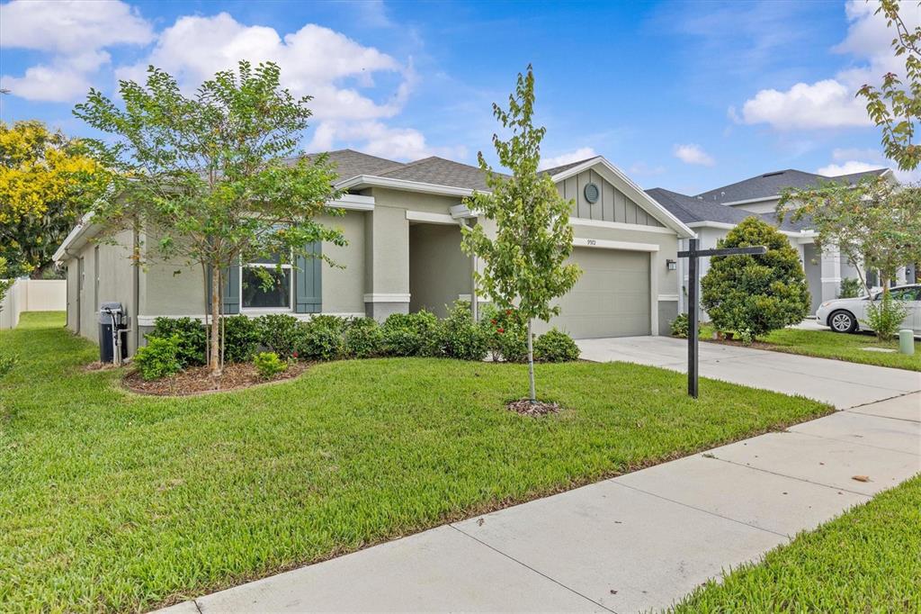 A single-story suburban house with a tan stucco exterior and a two-car garage — 9972 MESIC WOODS AVENUE, SEFFNER, FL