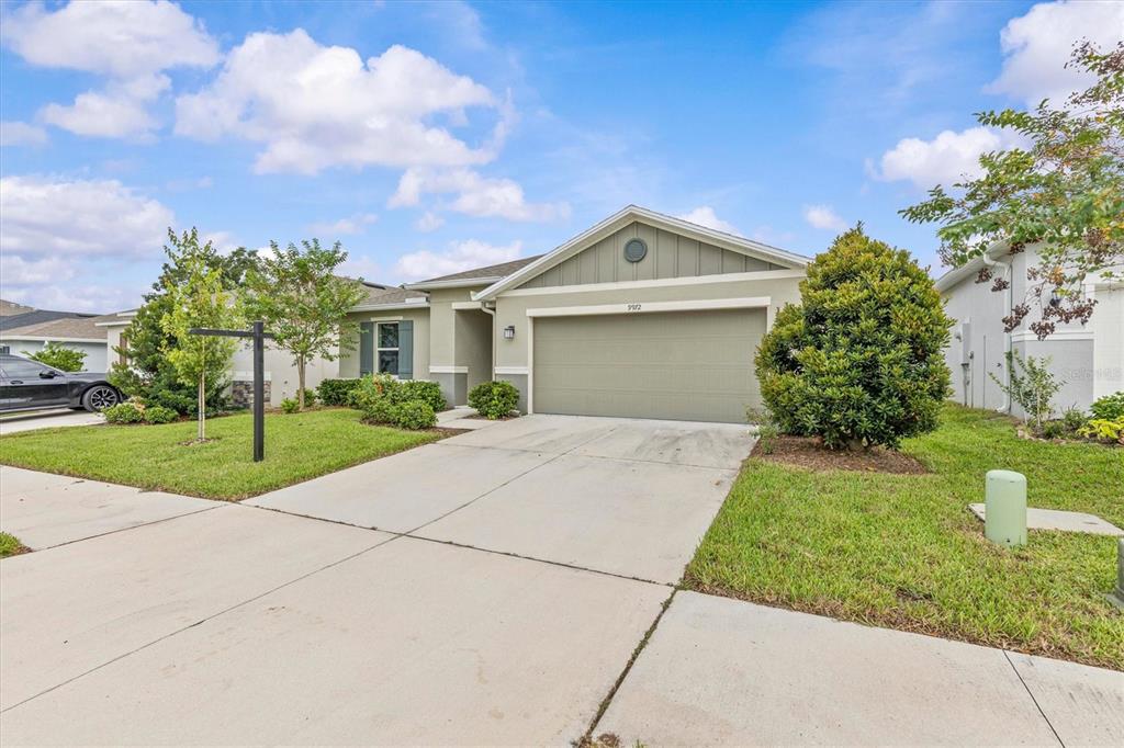 A covered entryway features a dark front door, a welcome sign, and a small table — 9972 MESIC WOODS AVENUE, SEFFNER, FL
