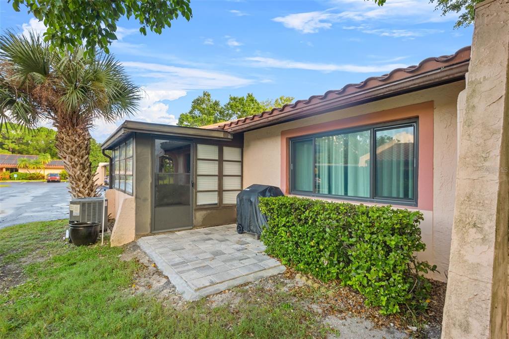 A patio with pavers sits next to a screened-in porch and a large window — 9669 86TH AVENUE UNIT 9669, SEMINOLE, FL