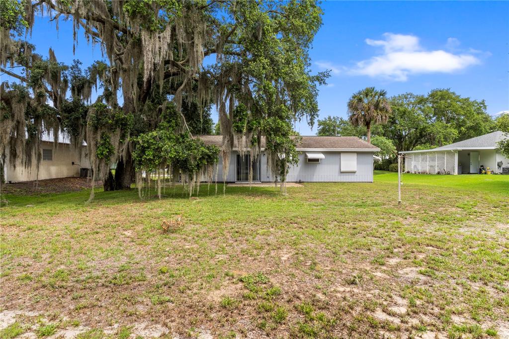 The backyard features a single-story house with a large oak tree draped in Spanish moss — 326 BELFAST TERRACE, SEBASTIAN, FL