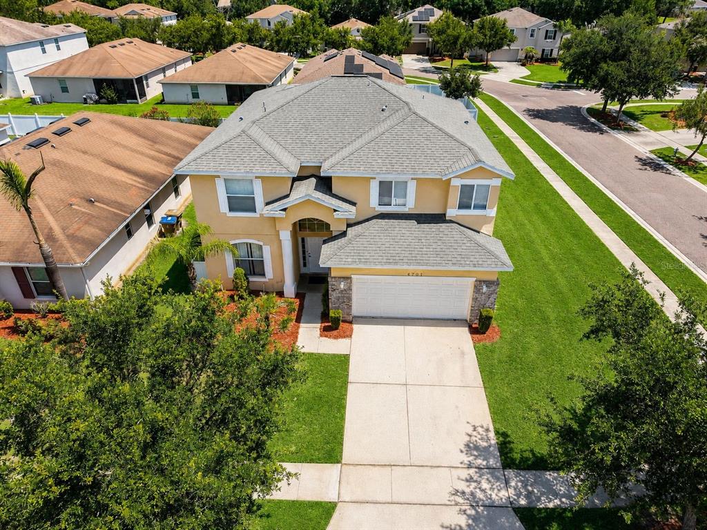 A two-story suburban house with a beige stucco exterior, a two-car garage, and a lawn — 4701 RUBY RED LANE, KISSIMMEE, FL