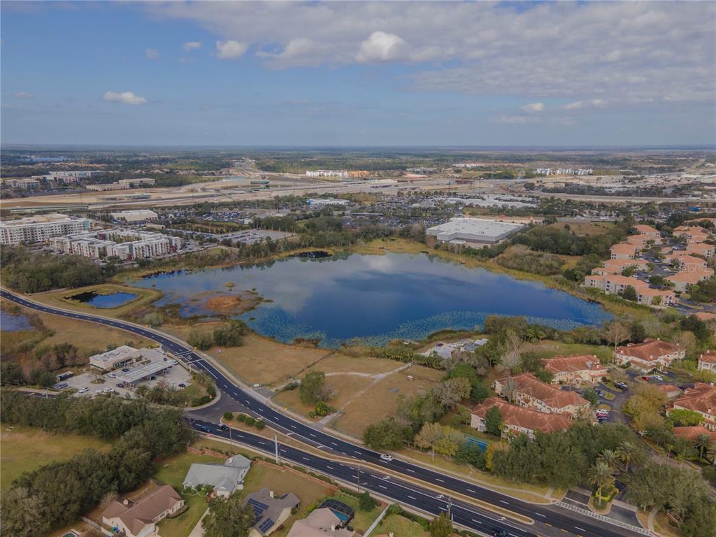 An aerial view shows a large lake surrounded by residential buildings, roads, and commercial properties — 4950 COUNTY ROAD 46A BOULEVARD, SANFORD, FL