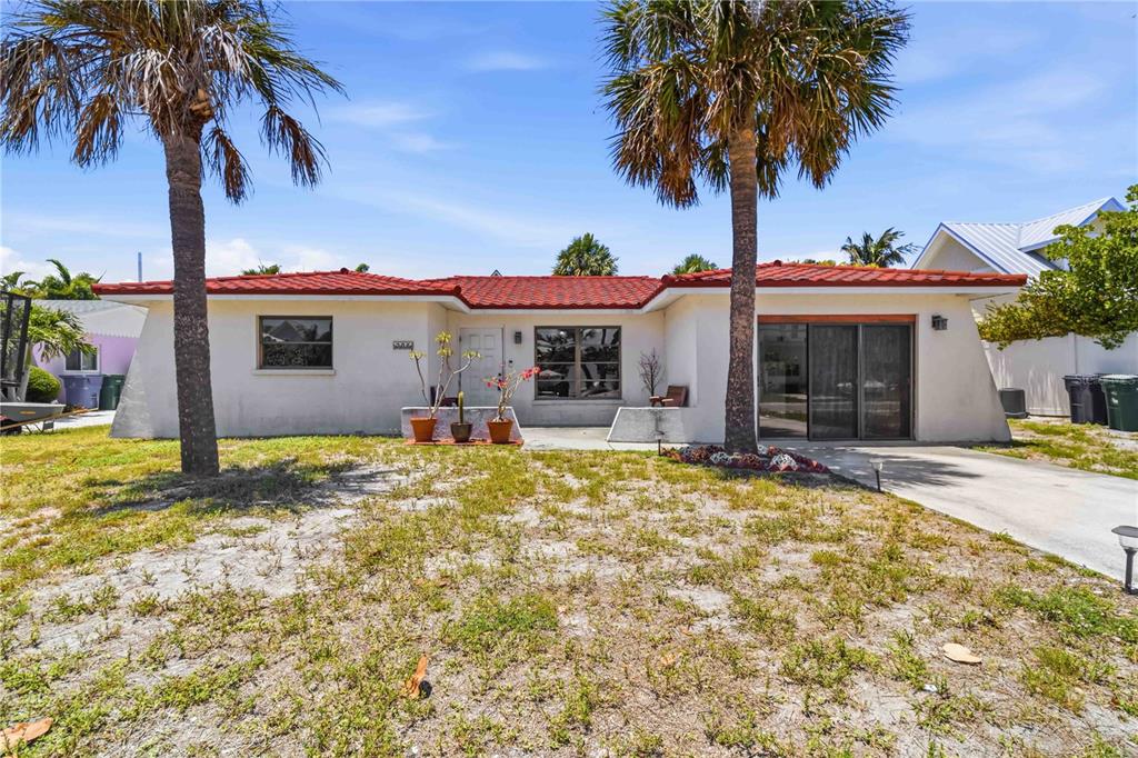 A white house with a red tile roof and a concrete driveway under a palm tree — 306 PALM AVENUE, ANNA MARIA, FL