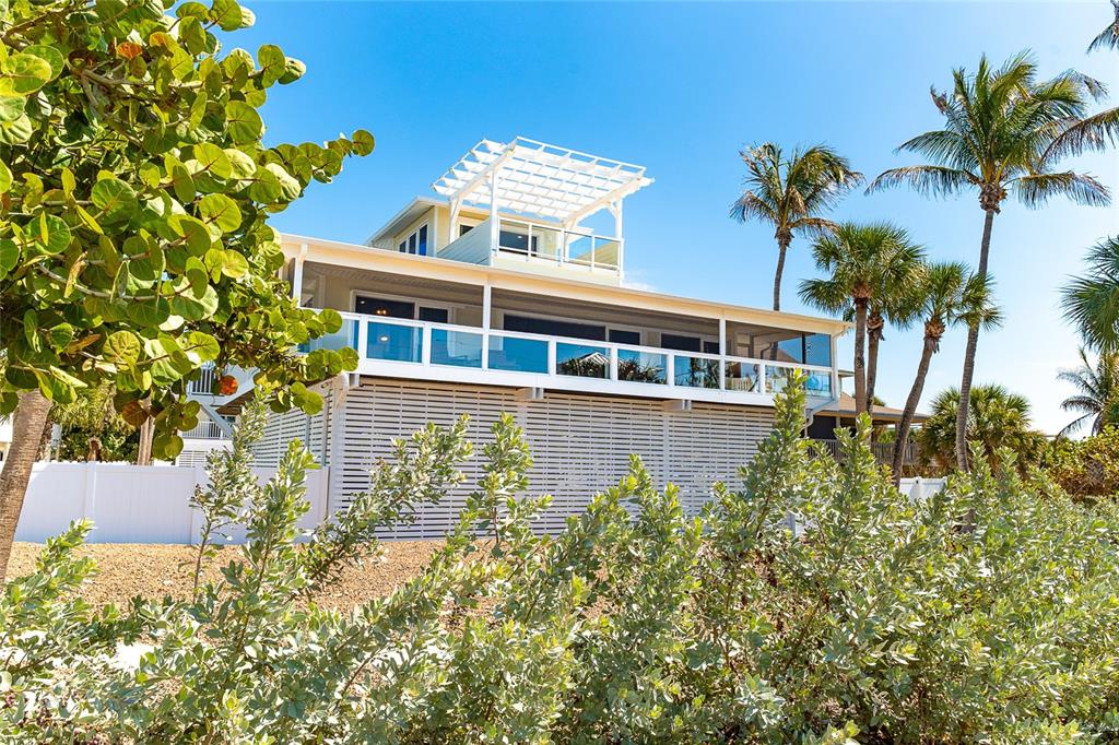 A multi-story coastal house features a screened balcony, a rooftop pergola, and lattice skirting — 230 N GULF BOULEVARD, PLACIDA, FL