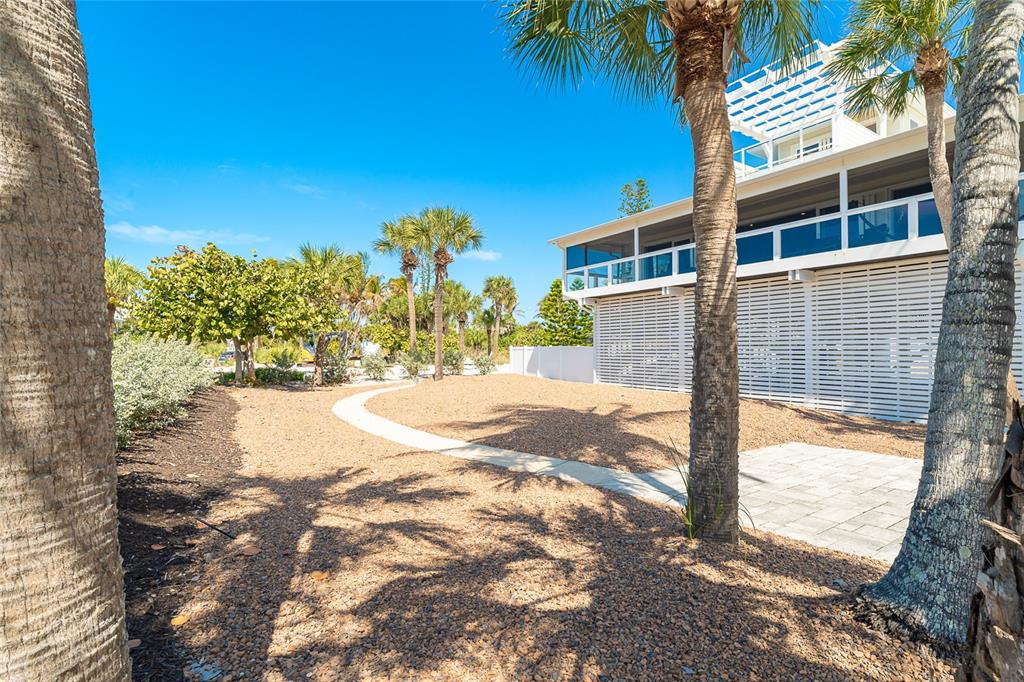 A gravel yard with a curved walkway leads to a multi-story house with white lattice — 230 N GULF BOULEVARD, PLACIDA, FL