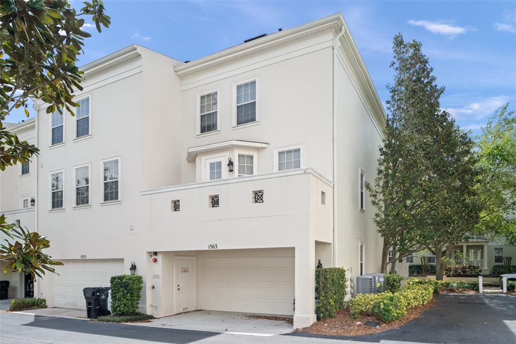 The exterior of a multi-story townhouse features a two-car garage and a second-floor balcony — 1563 COMMON WAY ROAD, ORLANDO, FL
