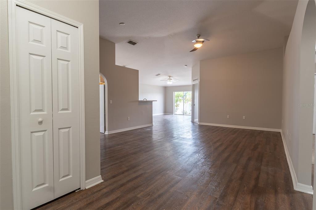 An open-concept living area features dark wood-look flooring, light gray walls, and two ceiling fans — 10917 BANYAN WOOD WAY, RIVERVIEW, FL