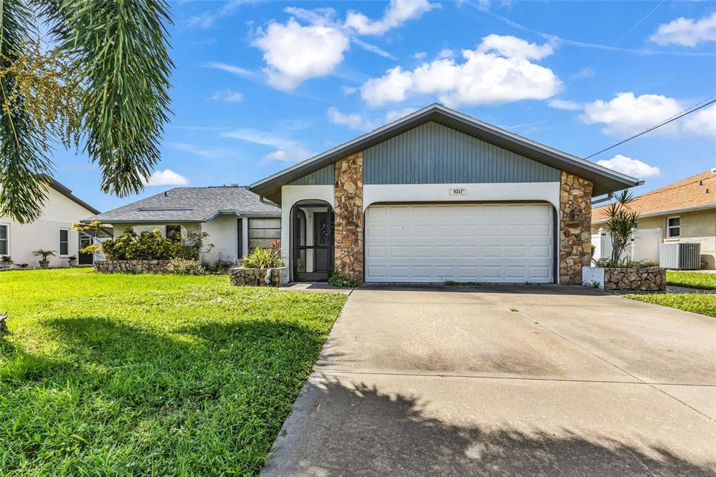 A single-story house with a white garage, stone accents, and a blue-gray gable roof — 9261 STEUBENVILLE AVENUE, ENGLEWOOD, FL