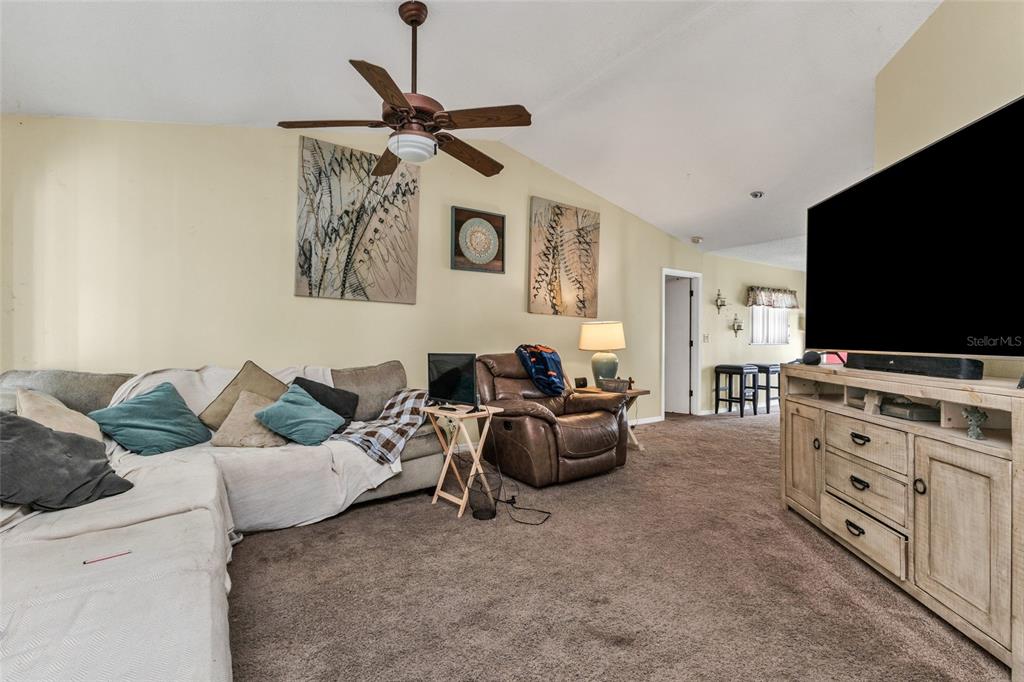 A living room features a sectional sofa, a brown recliner, and a large television console — 9261 STEUBENVILLE AVENUE, ENGLEWOOD, FL