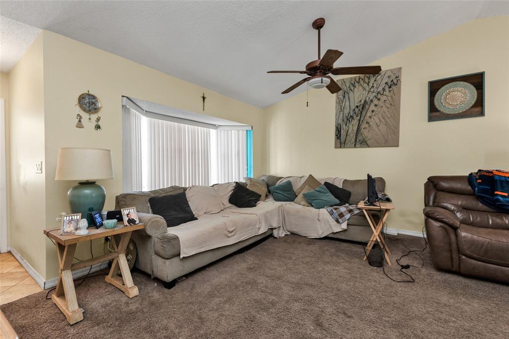 A living room features a large sectional sofa, brown carpeting, and a ceiling fan — 9261 STEUBENVILLE AVENUE, ENGLEWOOD, FL