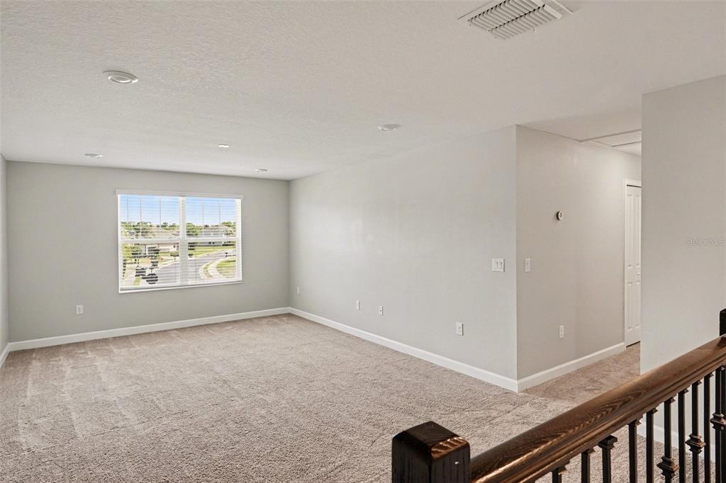A kitchen with a dark island and stainless steel appliances opens to a living area — 467 BRUNSWICK DRIVE, DAVENPORT, FL
