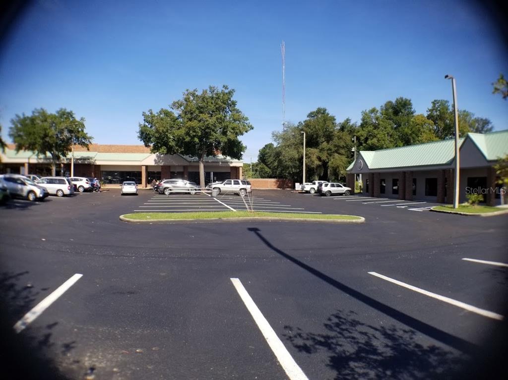 A parking lot sits in front of two commercial buildings under a clear blue sky — 1927 SW COLLEGE ROAD UNIT C, OCALA, FL