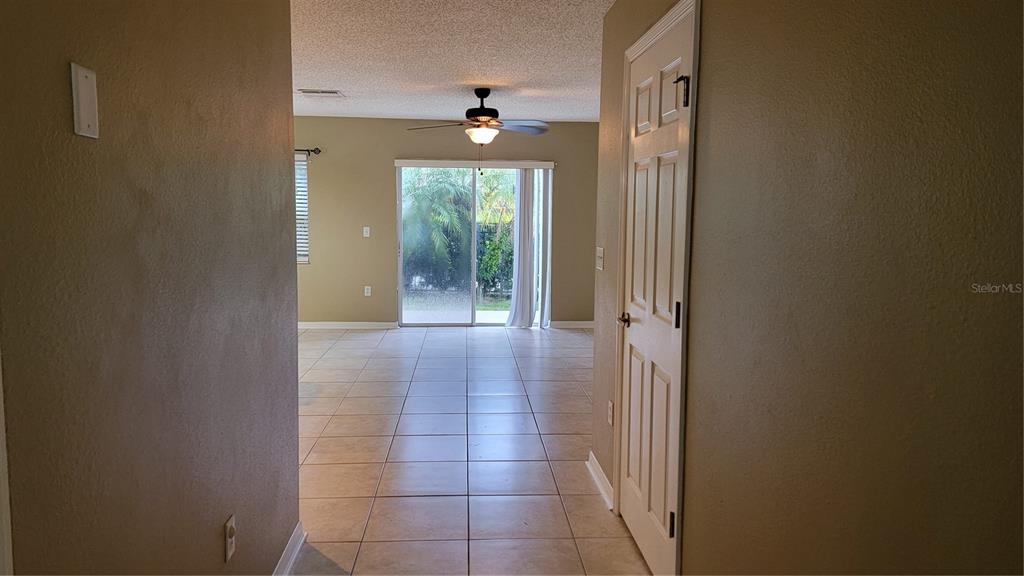 A tiled hallway leads into a living area with a ceiling fan and sliding glass doors — 2805 CLIFFE COURT, OVIEDO, FL