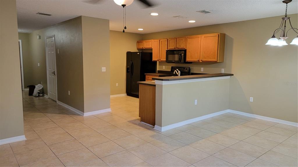 A kitchen with wood cabinets, a black refrigerator, and a breakfast bar overlooks a room — 2805 CLIFFE COURT, OVIEDO, FL