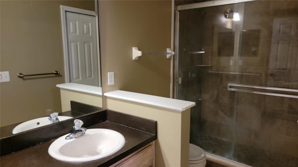 A bathroom features a vanity with a white sink, a mirror, and a glass-enclosed shower — 2805 CLIFFE COURT, OVIEDO, FL