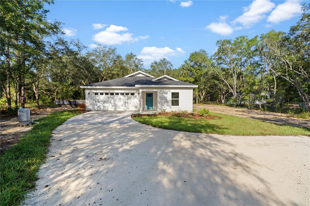 A newly constructed single-story house with white siding, a garage, and a covered porch — 8030 NE 102ND COURT, BRONSON, FL