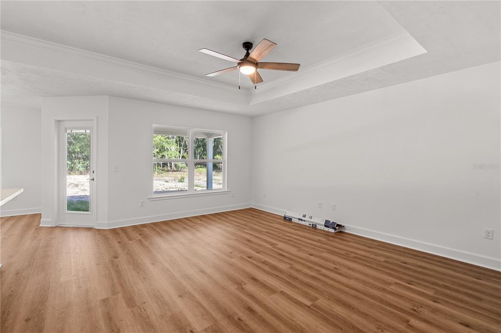 An open-concept living area features wood-look flooring, a tray ceiling, and a kitchen island — 8030 NE 102ND COURT, BRONSON, FL