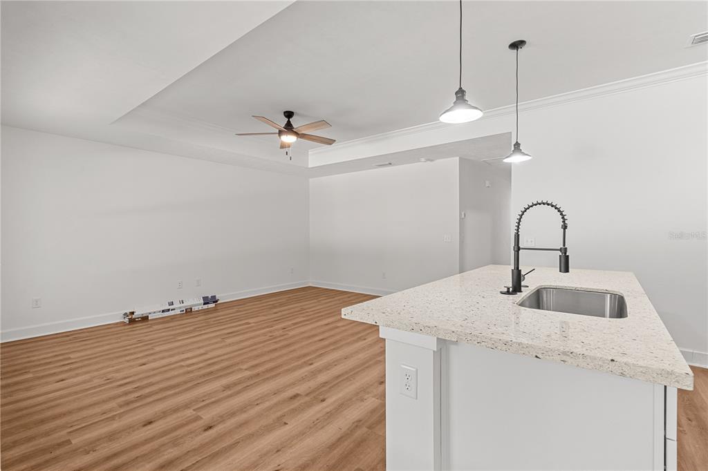 A kitchen with white cabinets, granite countertops, and an island opens to a dining area — 8030 NE 102ND COURT, BRONSON, FL
