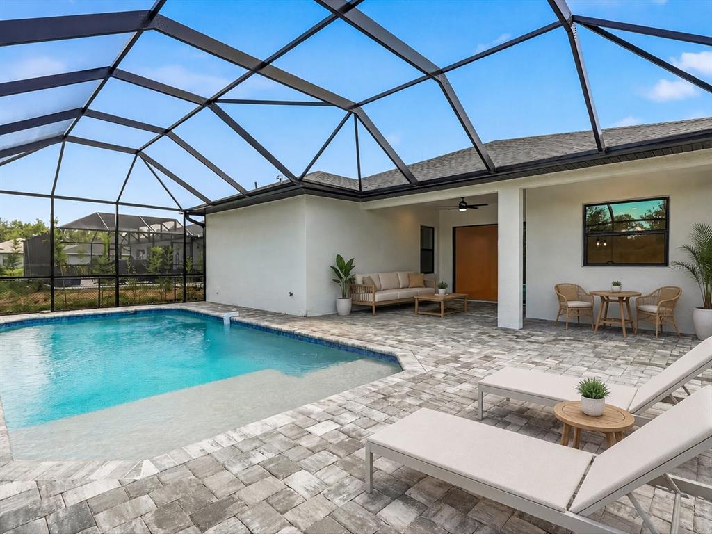 A screened-in patio features a swimming pool, lounge chairs, and a covered seating area — 108 LOMAS RD, ROTONDA WEST, FL