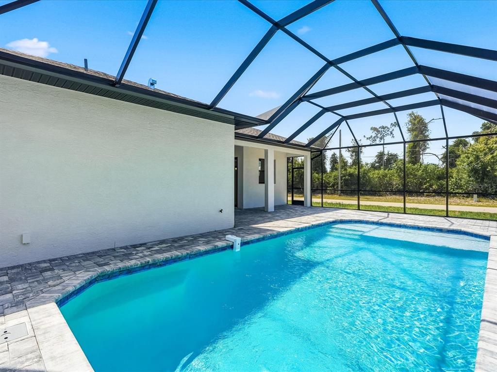 A swimming pool with a brick paver deck is enclosed by a screened lanai — 108 LOMAS RD, ROTONDA WEST, FL