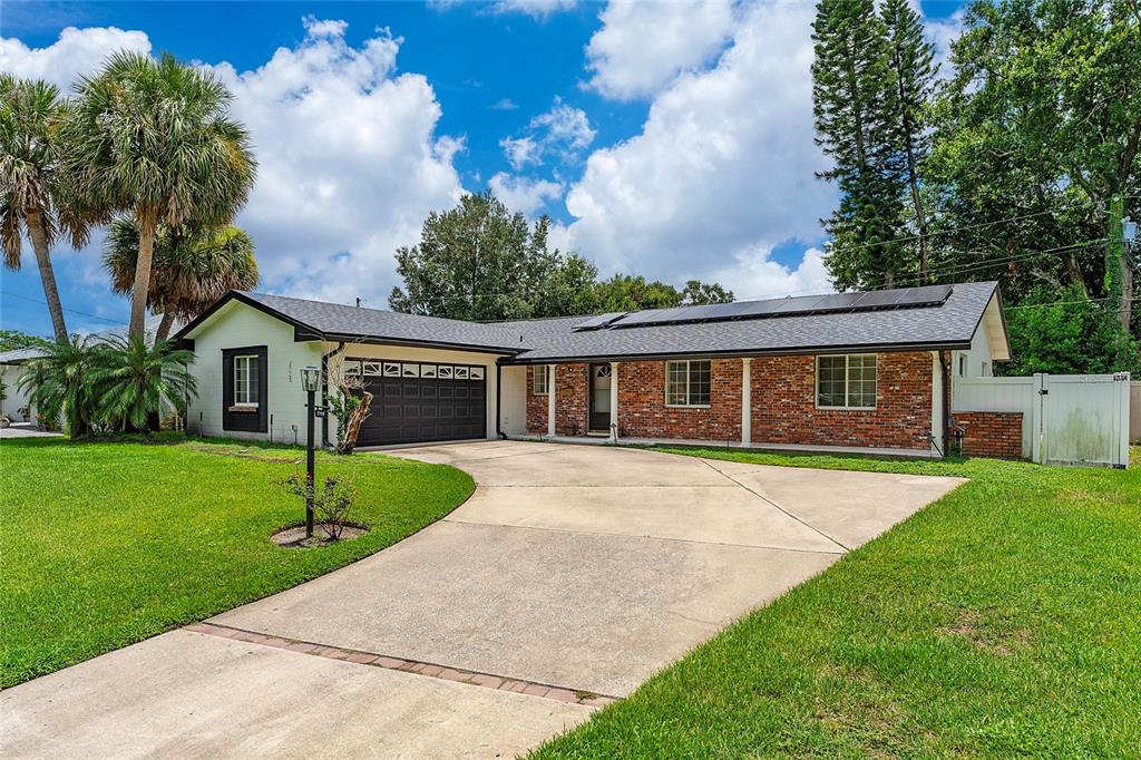 A single-story brick and stucco house with a dark garage door and solar panels — 2758 BANCHORY ROAD, WINTER PARK, FL