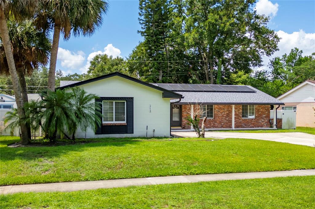 A single-story house with a white exterior, brick accents, and solar panels on the roof — 2758 BANCHORY ROAD, WINTER PARK, FL