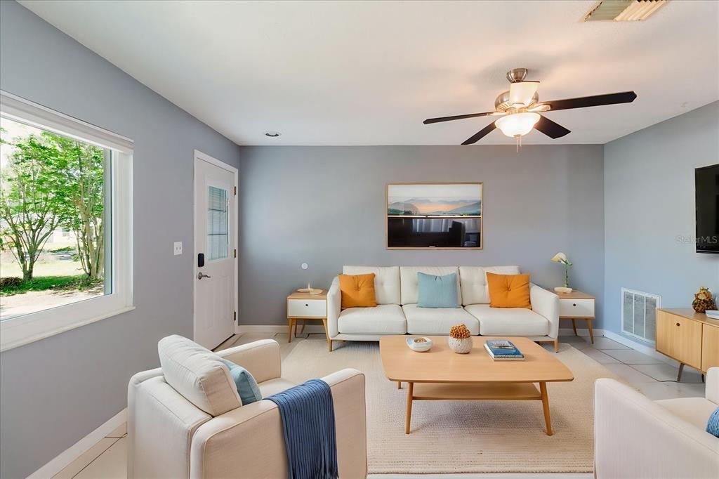A living room features a white sofa, two armchairs, a coffee table, and gray walls — 2009 PEPPERTREE COURT, OLDSMAR, FL