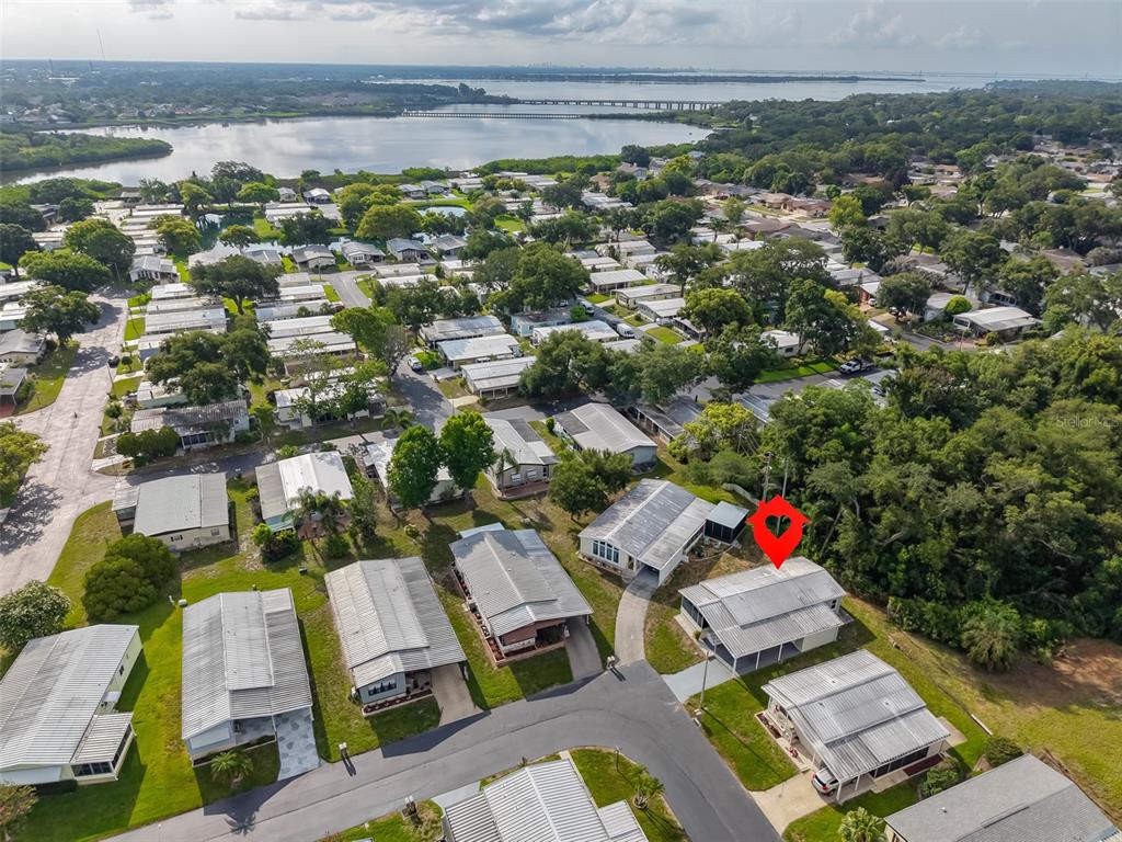 An aerial view shows a residential neighborhood of mobile homes near a large body of water — 168 BEECHWOOD DRIVE UNIT 67, SAFETY HARBOR, FL