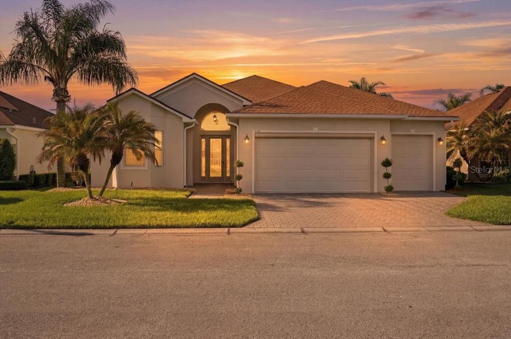 A single-story house with a tan stucco exterior, a three-car garage, and a palm tree — 4193 STONE CREEK LOOP, LAKE WALES, FL