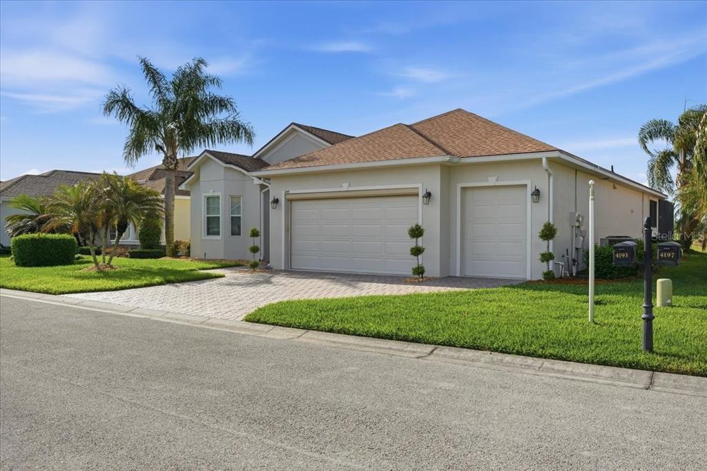 A single-story house with a beige exterior, a paved driveway, and a three-car garage — 4193 STONE CREEK LOOP, LAKE WALES, FL