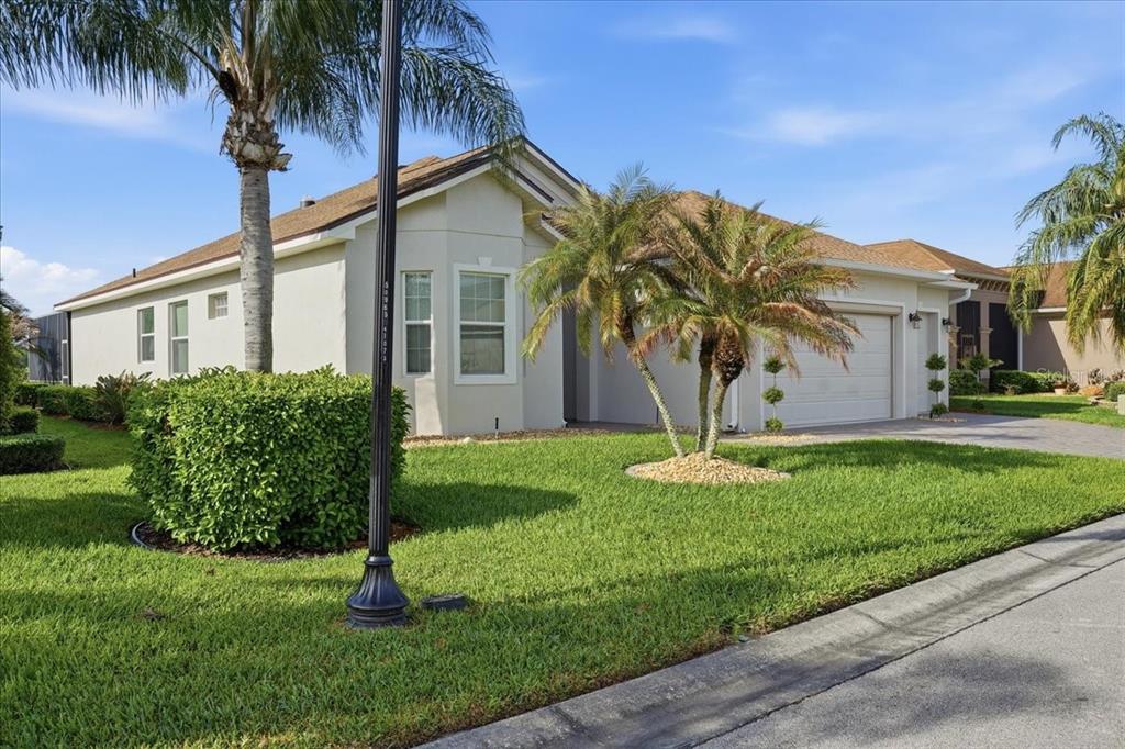 A single-story house with a beige exterior, a two-car garage, and palm trees in front — 4193 STONE CREEK LOOP, LAKE WALES, FL