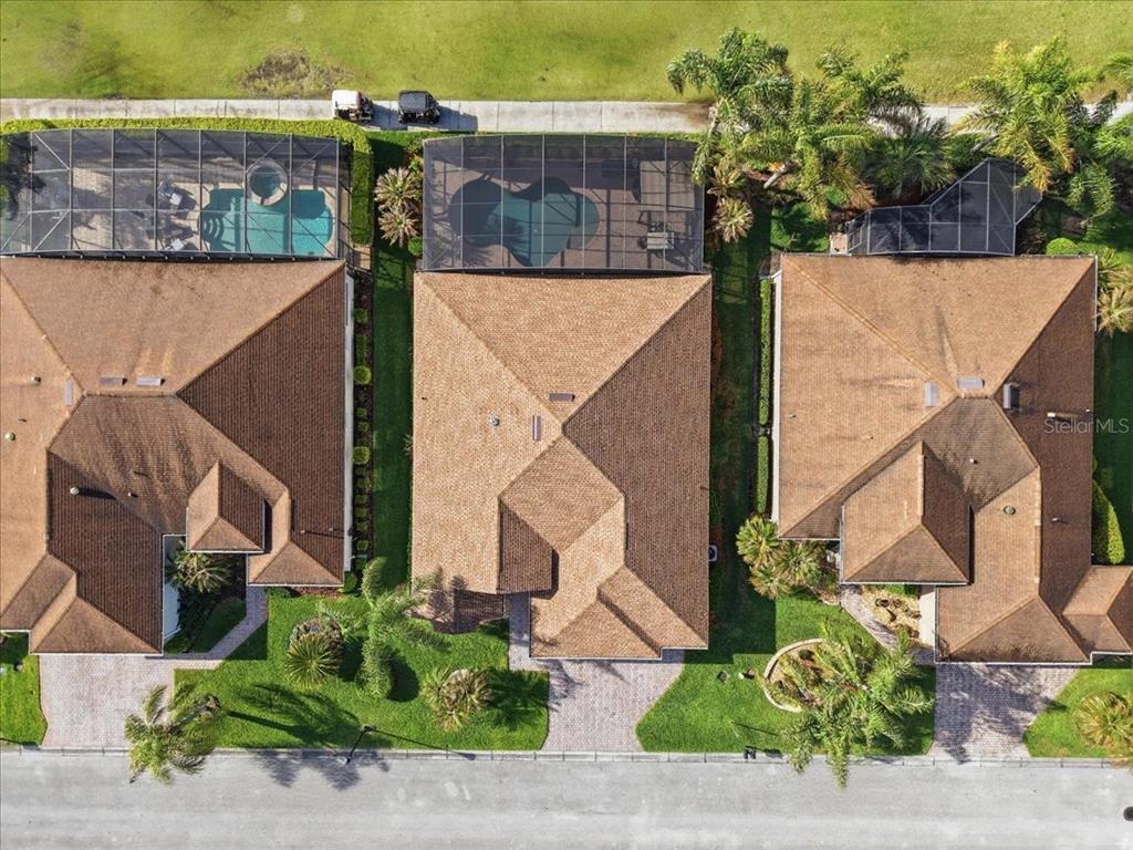 Aerial view of three suburban houses with screened-in pools and driveways facing a street — 4193 STONE CREEK LOOP, LAKE WALES, FL