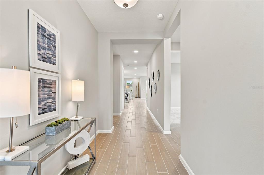 A modern kitchen features white cabinetry, a central island with a sink, and tile flooring — 3206 WOLF LAKE AVENUE, APOPKA, FL