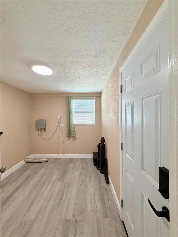 A small room with light wood-look flooring, beige walls, a window, and a white door — 110 S CORONA AVENUE, CLEARWATER, FL