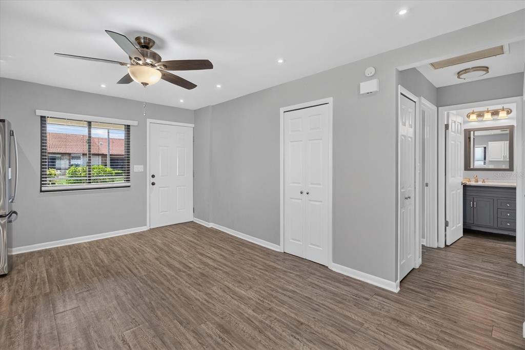 A room with gray walls, wood-look flooring, a ceiling fan, and an adjacent bathroom — 7360 ULMERTON ROAD UNIT 2E, LARGO, FL