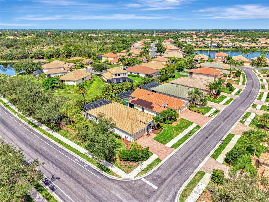 An aerial view shows suburban houses with tile roofs and swimming pools near a lake — 11783 PUMA PATH, VENICE, FL