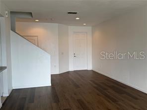 An interior view of a living area with dark wood flooring and a white front door — 1550 PORTOFINO MEADOWS BOULEVARD, ORLANDO, FL