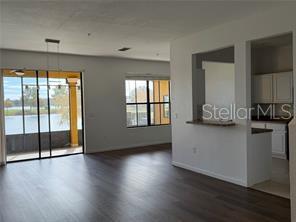An open living area with dark wood flooring, a kitchen pass-through, and sliding glass doors — 1550 PORTOFINO MEADOWS BOULEVARD, ORLANDO, FL