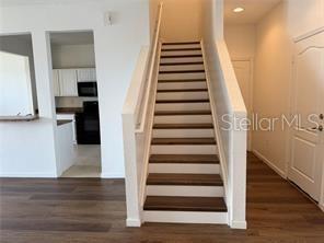A staircase with dark wood treads and white risers leads to an upper level — 1550 PORTOFINO MEADOWS BOULEVARD, ORLANDO, FL