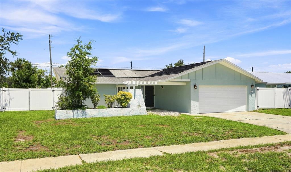 A light blue single-story house features a white garage door and solar roof panels — 13691 SERENA DRIVE, LARGO, FL
