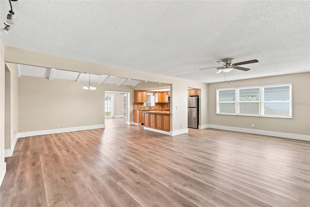 An open-concept living area with wood-look flooring, a ceiling fan, and an adjacent kitchen — 13691 SERENA DRIVE, LARGO, FL