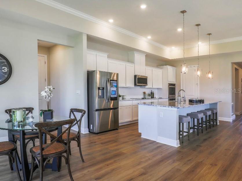 A kitchen with white cabinets, stainless steel appliances, a large island, and wood-look flooring — 930 BUCKEYE DRIVE, LADY LAKE, FL
