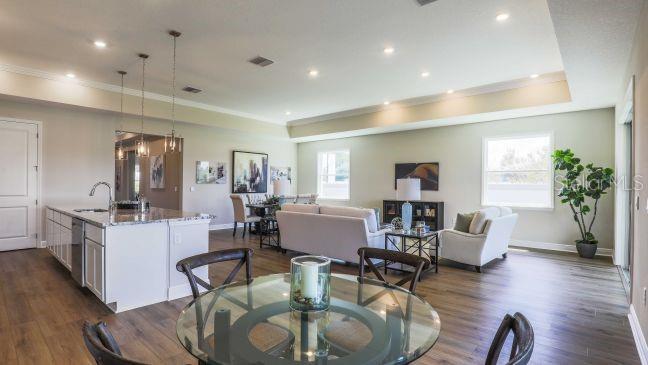An open-concept living area features a kitchen island, dining table, and seating area with wood floors — 930 BUCKEYE DRIVE, LADY LAKE, FL