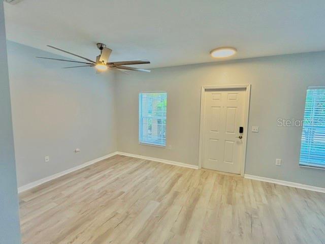A room with light wood-look flooring, a ceiling fan, a white door, and two windows — 6218 FLAGFISH COURT UNIT 102, BRADENTON, FL