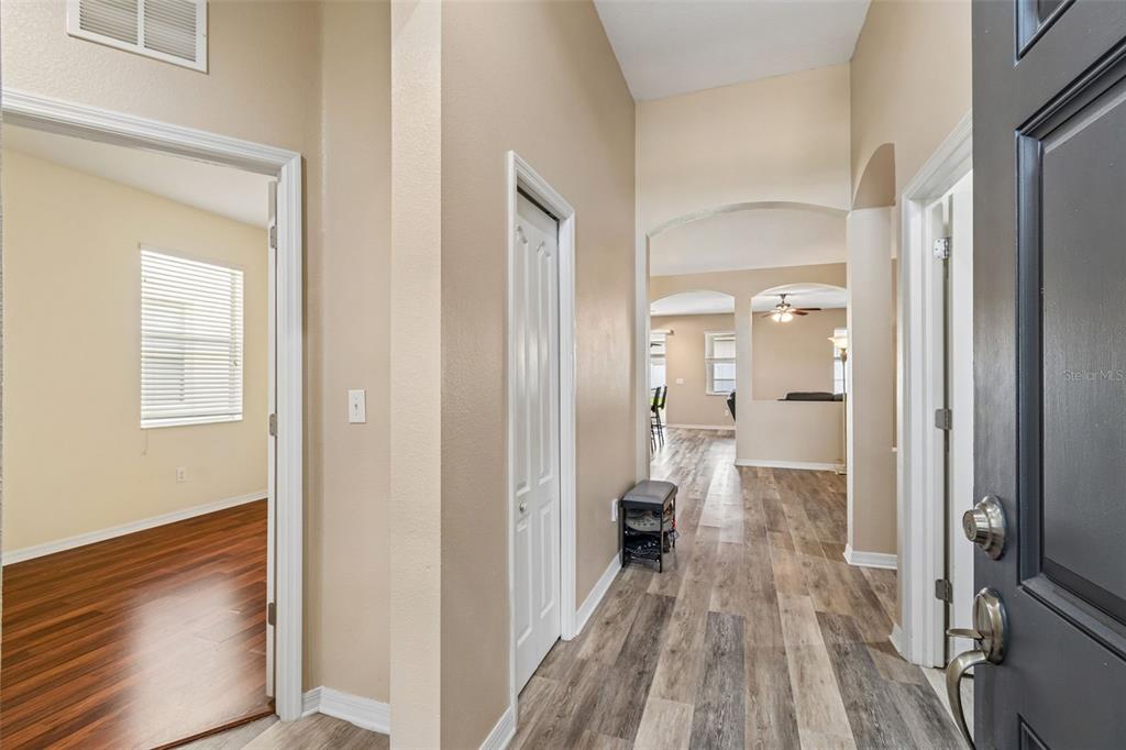 An entryway with wood-look flooring leads into a living area with arched architectural details — 211 FAIRMONT DRIVE, SPRING HILL, FL